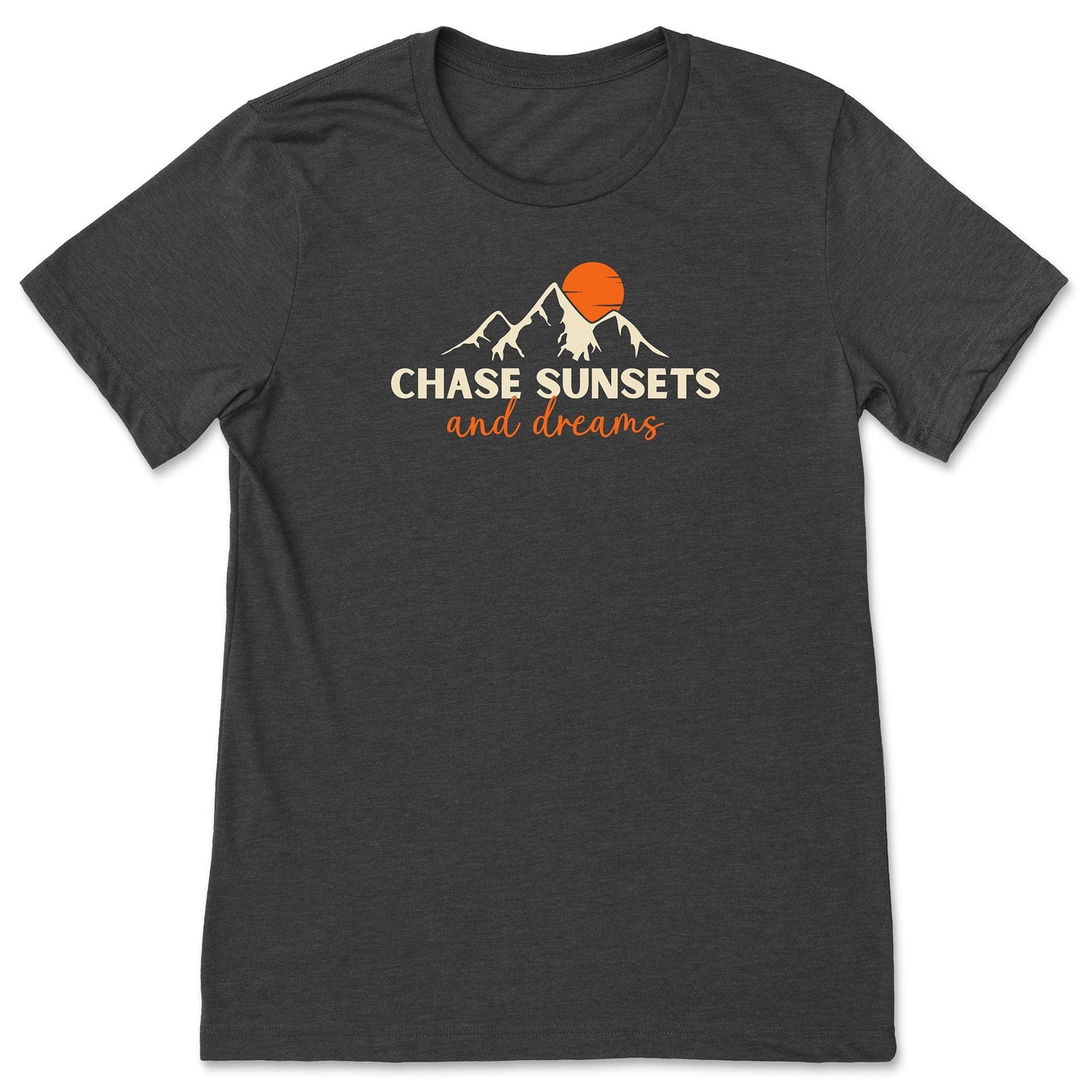 A dark grey, chasing sunsets t-shirt that has mountains with an orange sunset and says, "Chase Sunsets and Dreams."