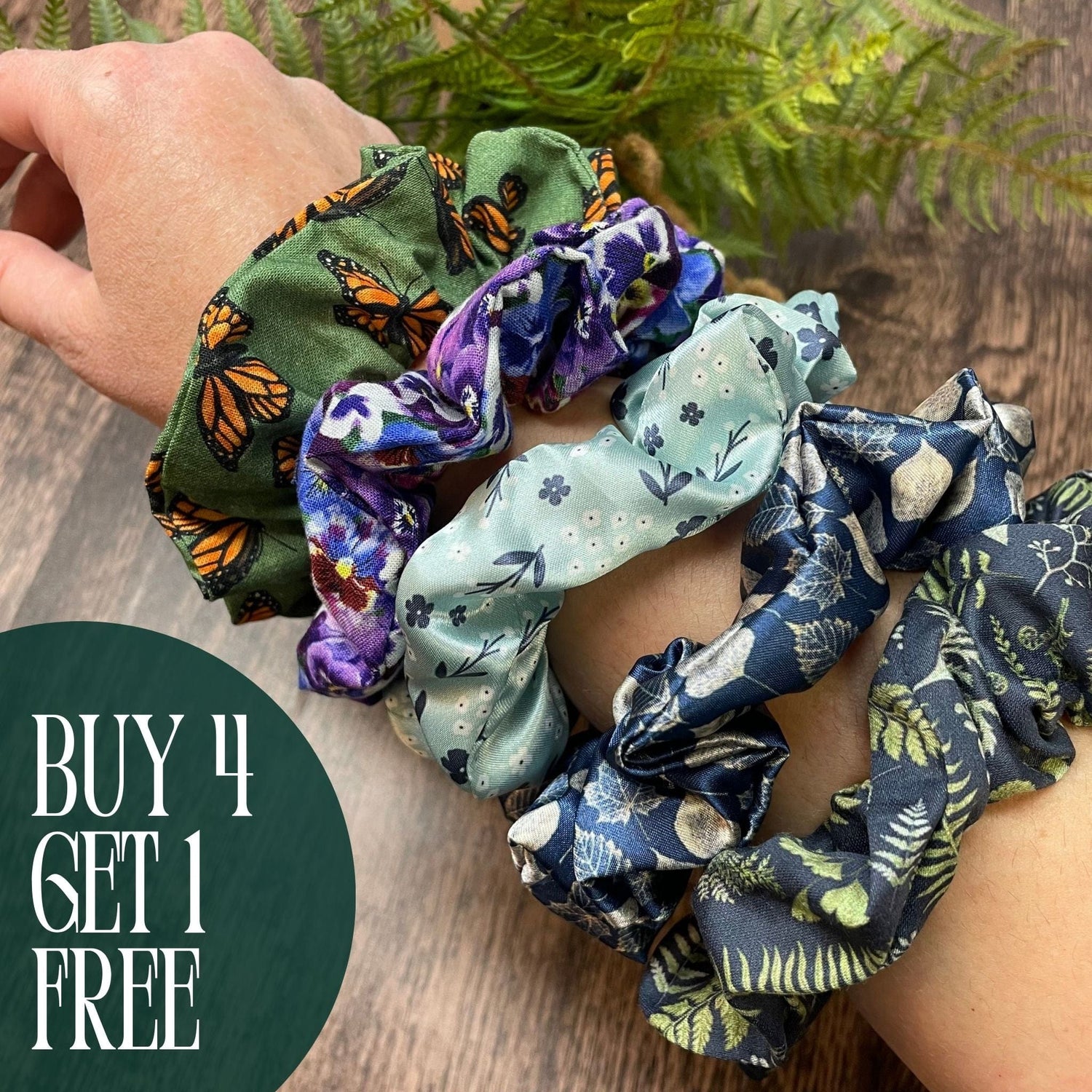 A group of colorful, nature-inspired scrunchies on someone's arm