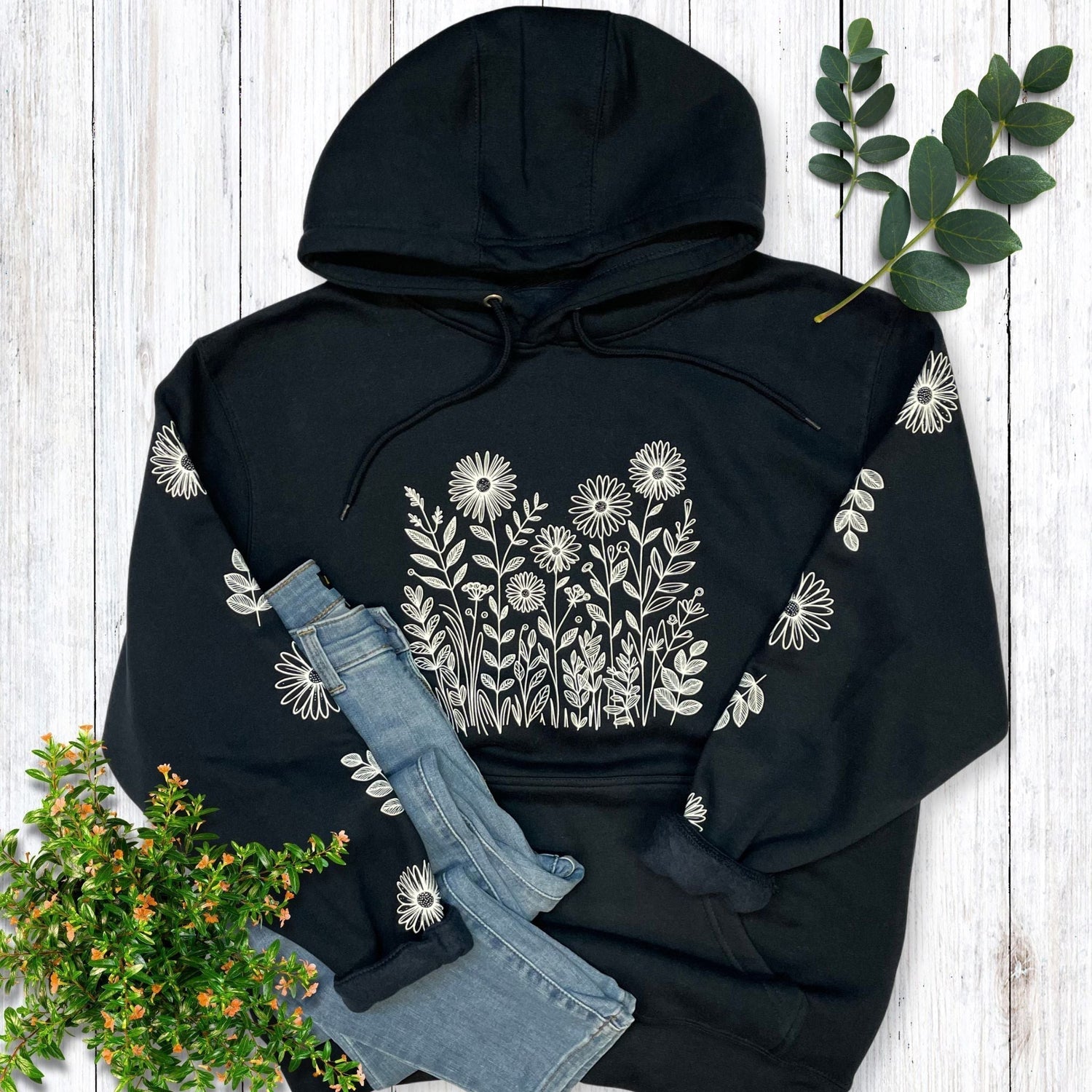 A navy, nature hoodie for flower lovers that has white wildflowers on the front and down both sleeves.
