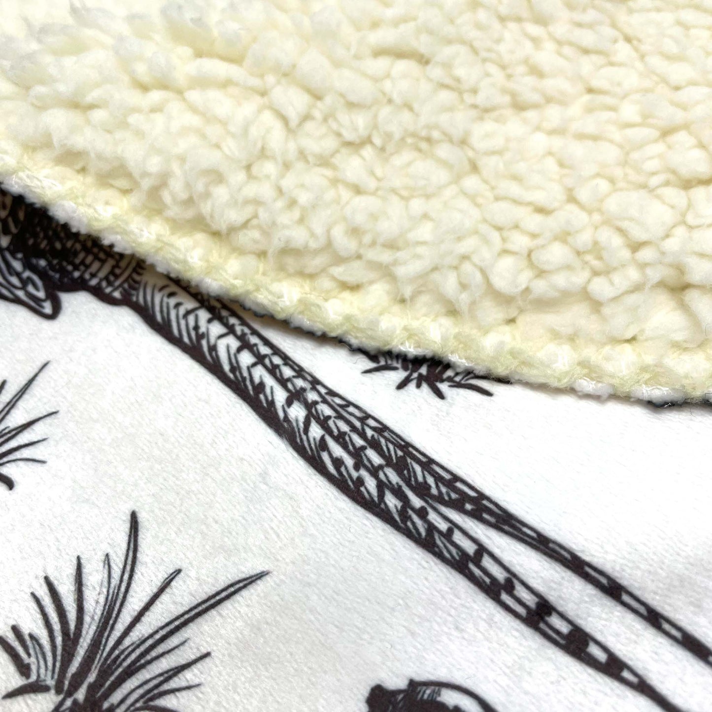 A close-up of a sherpa throw blanket with a pheasant patterned front with a sherpa fleece backing.