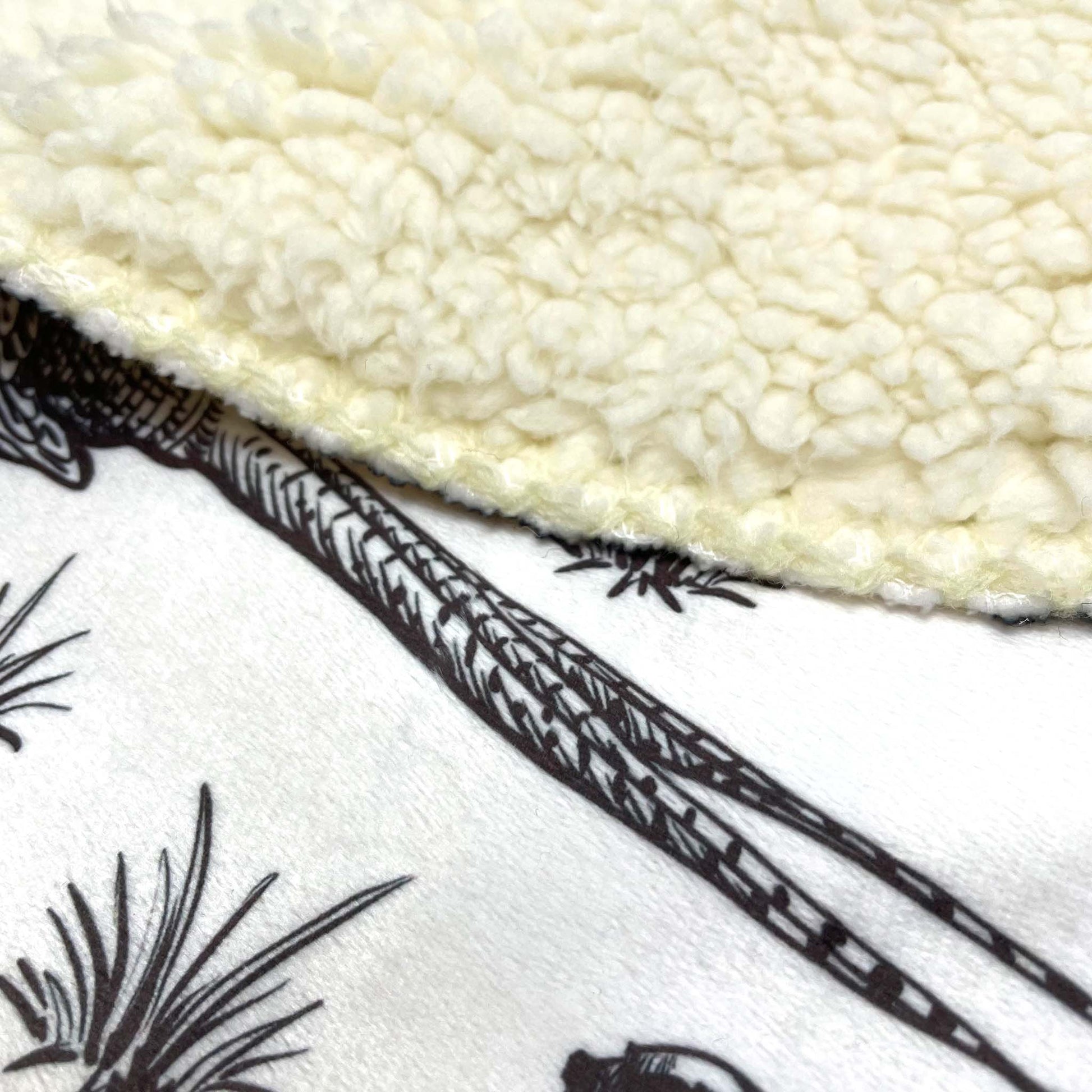 A close-up of a sherpa throw blanket with a pheasant patterned front with a sherpa fleece backing.