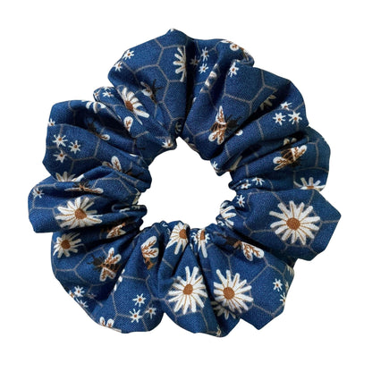 Blue floral scrunchie that has daisies and honey bees on a honeycomb pattern.
