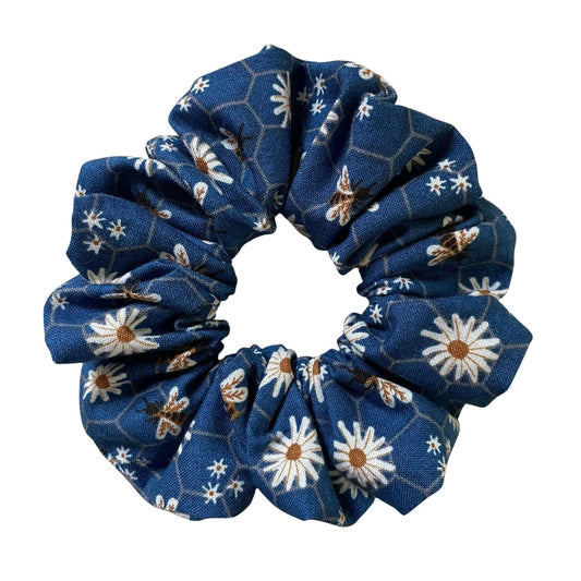 Blue floral scrunchie that has daisies and honey bees on a honeycomb pattern.