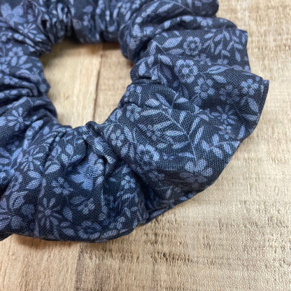Close-up of a blue floral patterned scrunchie on a wooden surface
