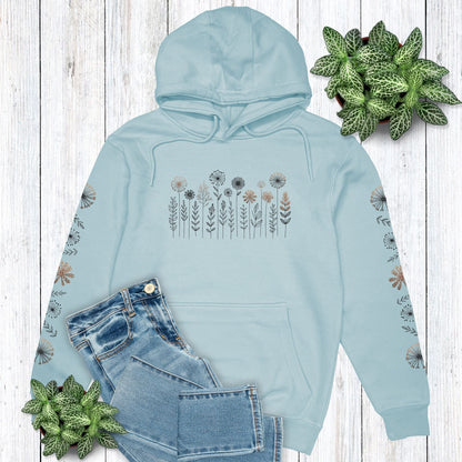 Light blue floral hoodie with a cute flower design on the front and down both sleeves, laying on a wooden surface with plants.