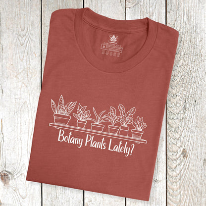 A folded, clay-colored, short-sleeve, funny plant t-shirt for gardeners and botanists that has a design with potted plants and says, "Botany Plants Lately?"