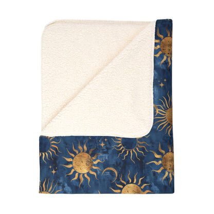 Folded sherpa blanket featuring a vibrant blue background with a celestial motif of sun, moon, and stars.