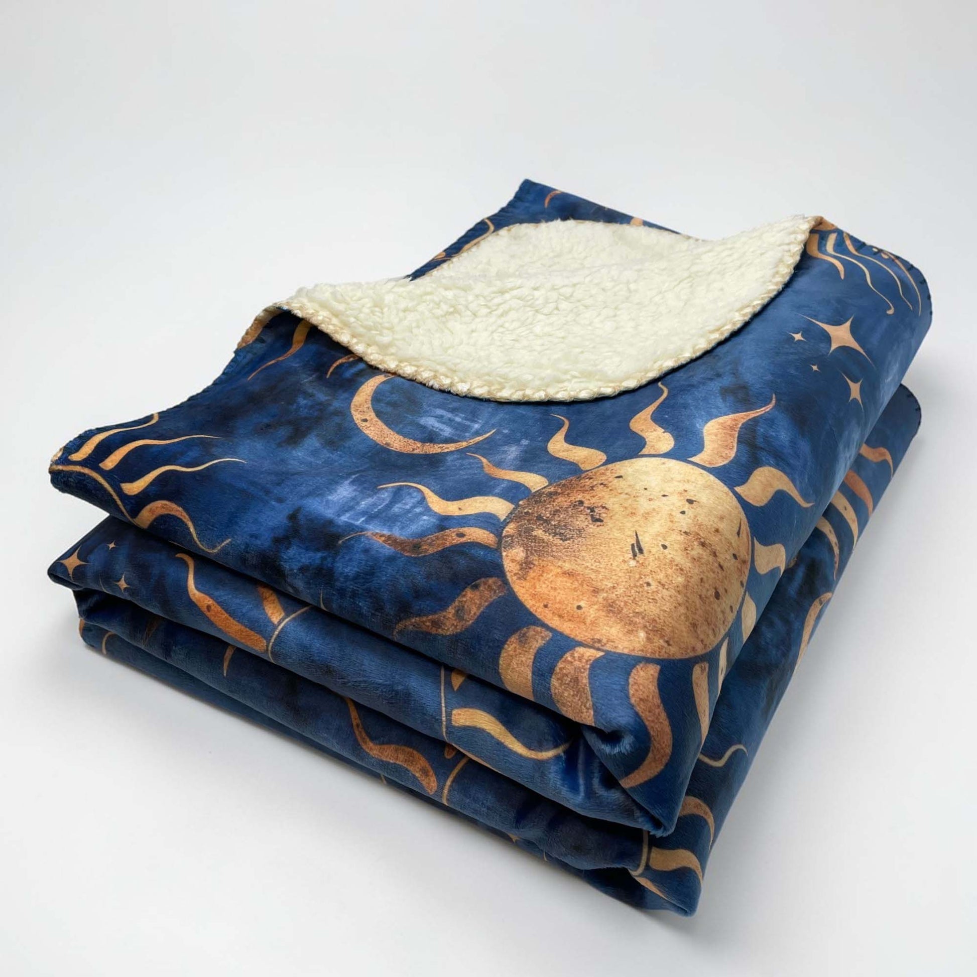 Folded sherpa blanket with celestial pattern on a white background