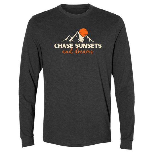 A dark grey, long-sleeve chasing sunsets shirt for nature lovers. Has an image of a mountain range and sun and says, "Chase Sunsets and Dreams."