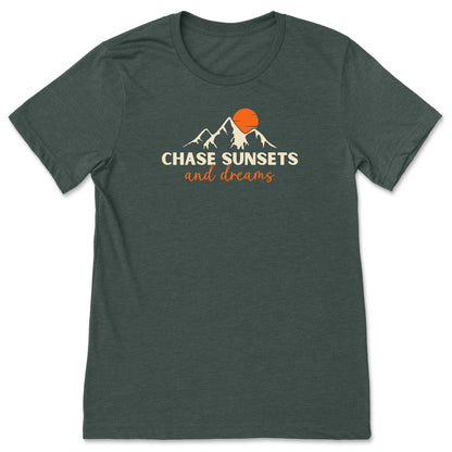 A forest green, chasing sunsets t-shirt that has mountains with an orange sunset and says, "Chase Sunsets and Dreams."