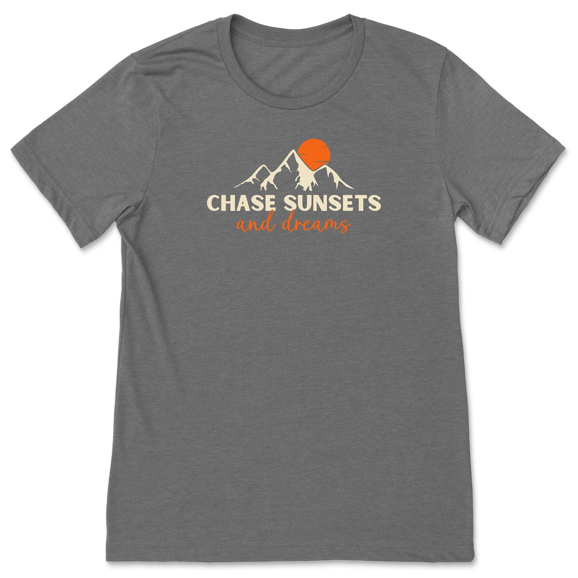 A grey chasing sunsets t-shirt that has mountains with an orange sunset and says, "Chase Sunsets and Dreams."