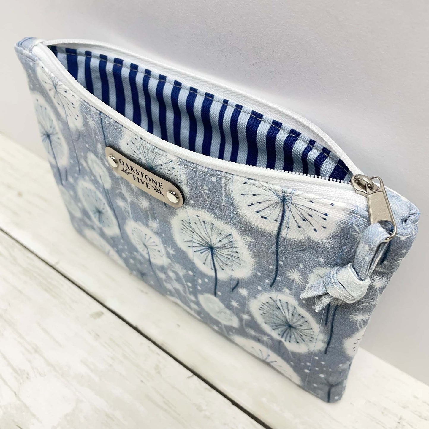 Fabric zipper pouch with dandelion pattern on a wooden surface