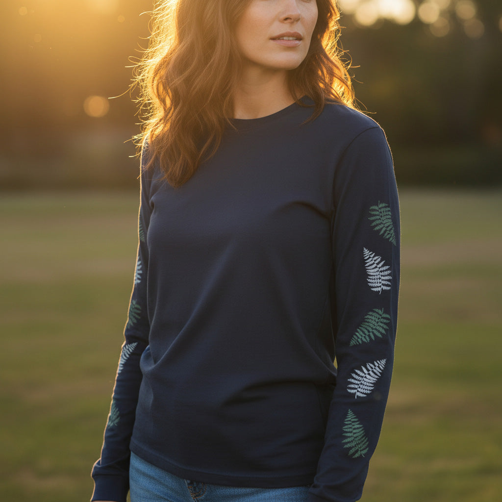 Woman standing outdoors, wearing a navy long sleeve shirt that has ferns down the sleeves.