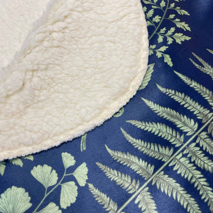 Close-up of the sherpa backside and printed front of a ferns and leaves sherpa blanket