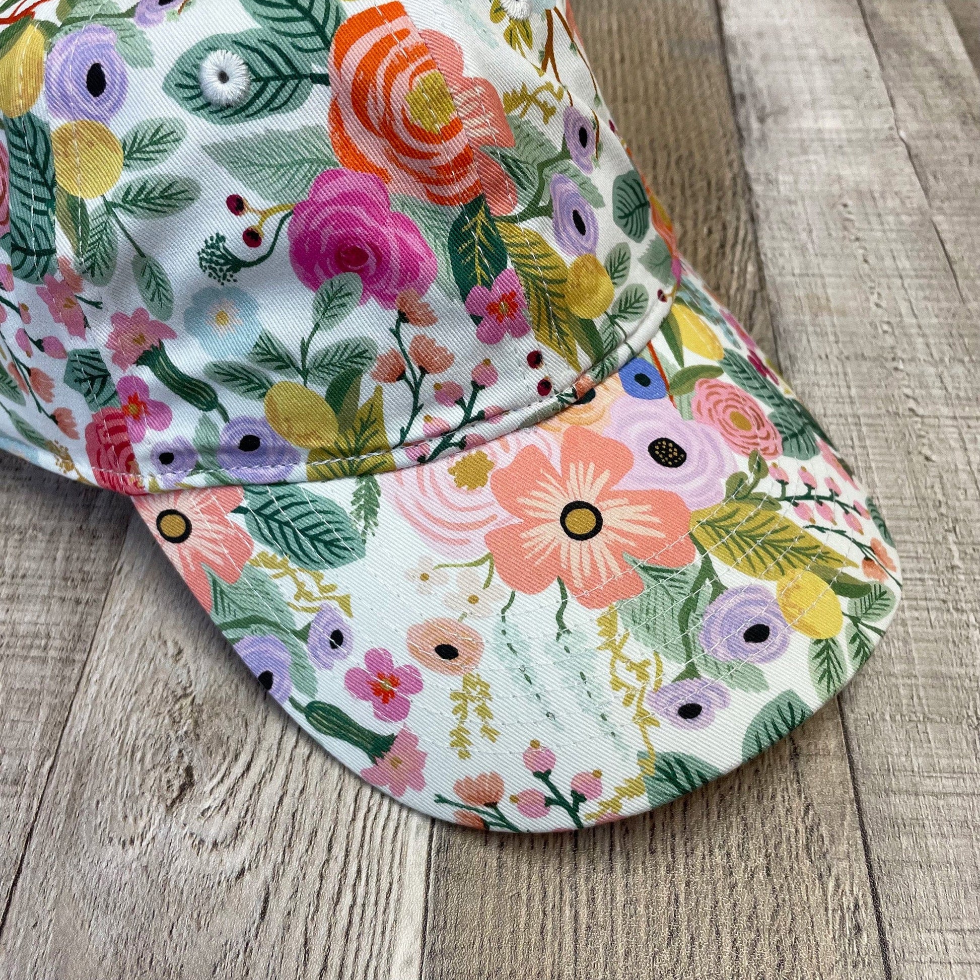 A cheerful, women's floral baseball hat with a vibrant and colorful flower pattern.
