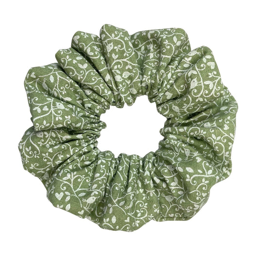 Green scrunchie with white floral and bird pattern on a white background