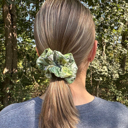 Girl standing in the woods wearing a green succulent scrunchie in her hair