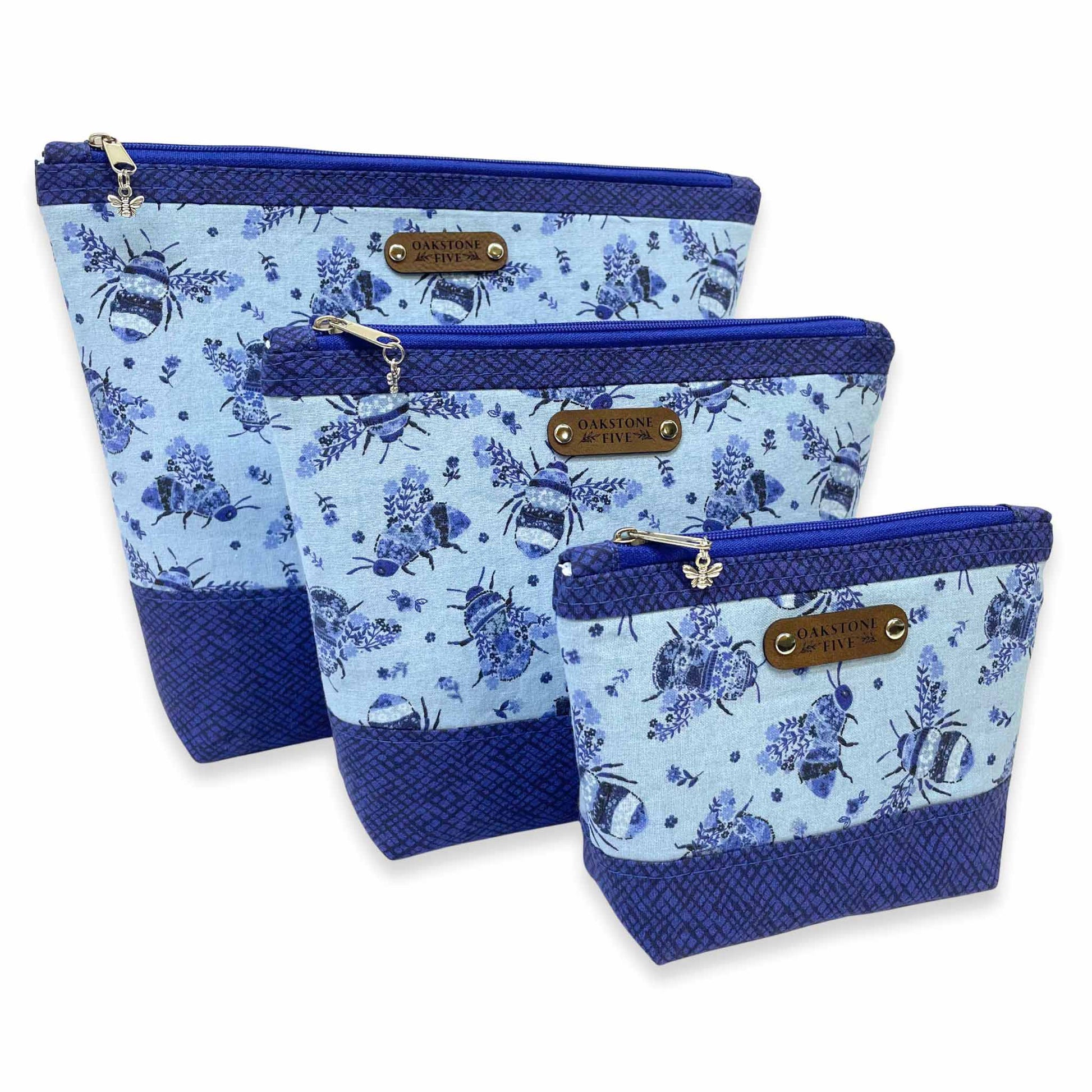 Three sizes of a blue floral zipper pouch with a bumble bee design on a white background