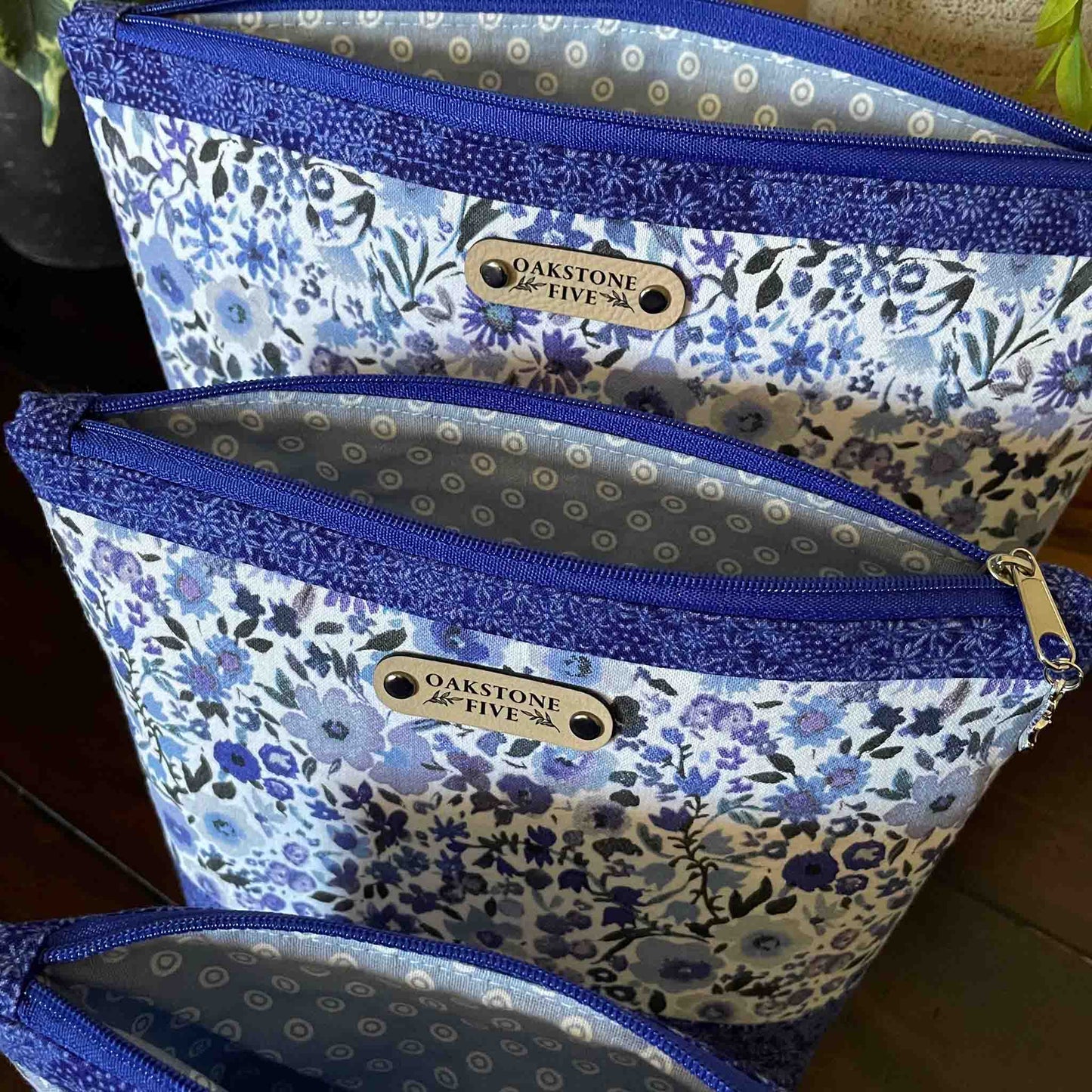 Set of three blue floral-patterned zipper pouches with pale blue dotted fabric on the inside.