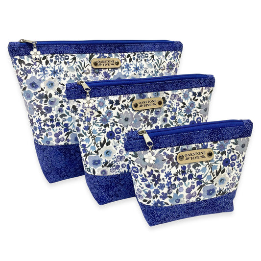 Set of three blue floral-patterned zipper pouches with blue accents on a white background