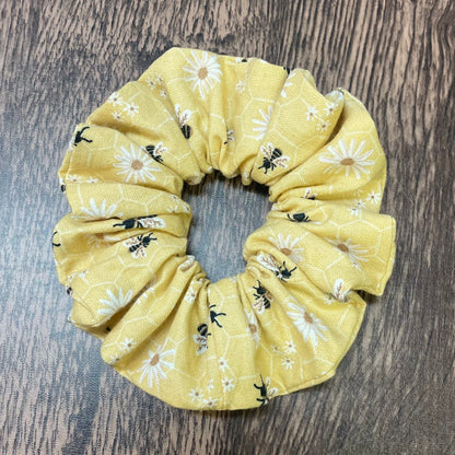 Yellow scrunchie with honey bee and floral pattern on a wood background
