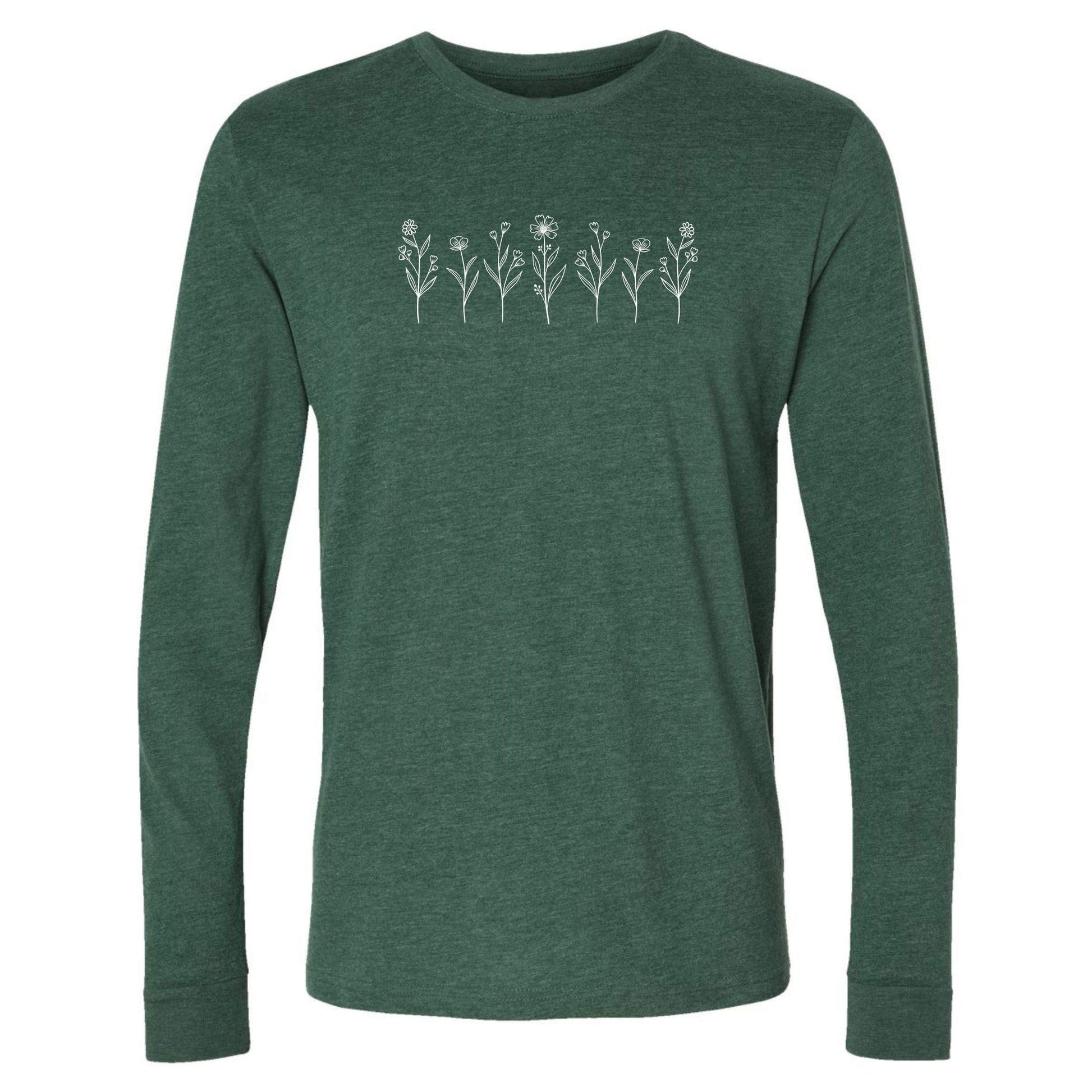 A cute, green, long-sleeve wildflower t-shirt for nature and plant lovers that has a design on across the chest of several small white wildflowers in a  row.
