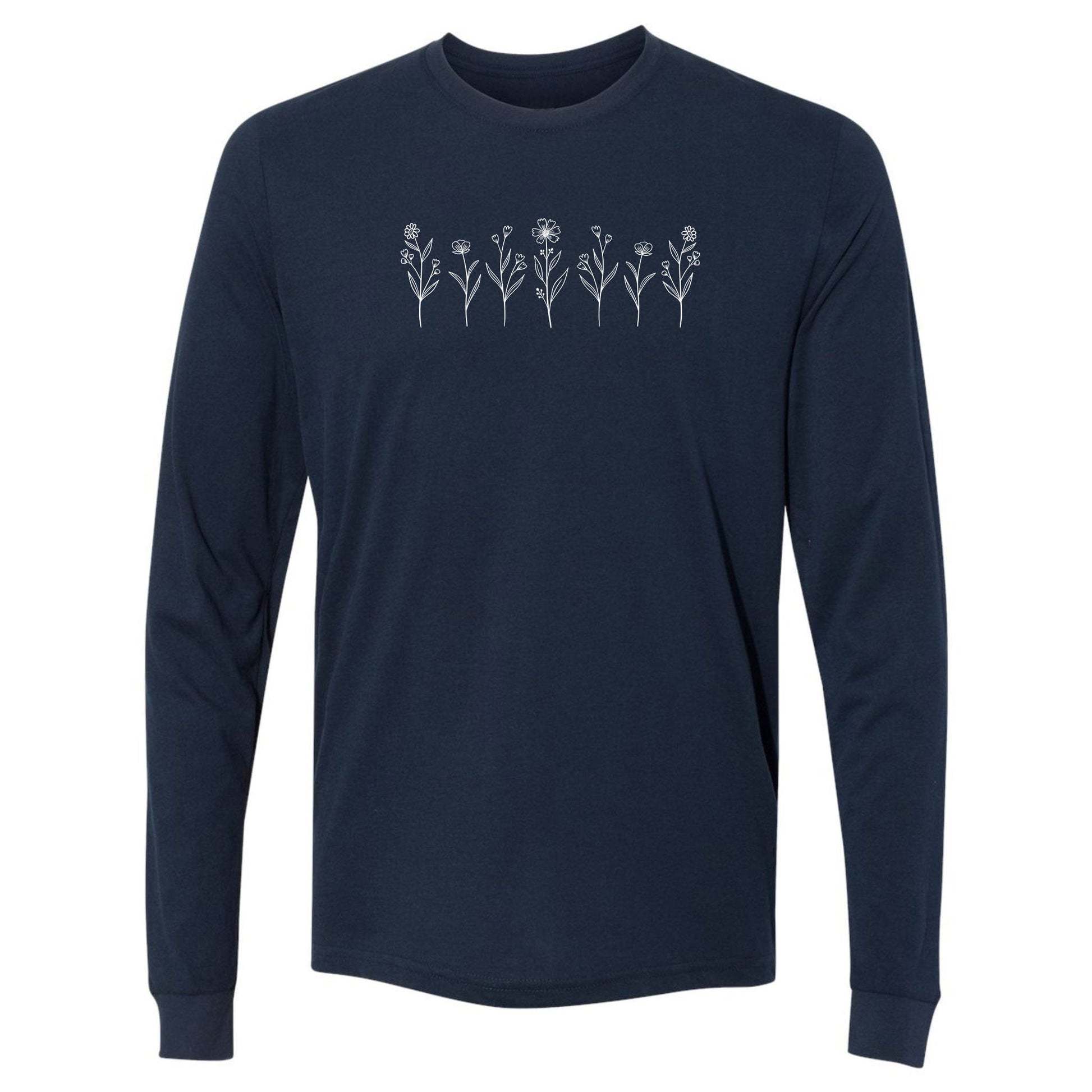A cute, navy, long-sleeve wildflower t-shirt for nature and plant lovers that has a design on across the chest of several small white wildflowers in a  row.