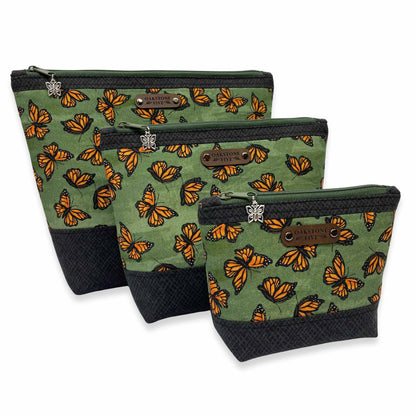 Three green zipper pouches with monarch butterfly pattern on a white background