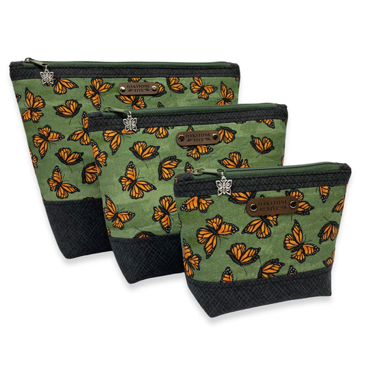 Three green zipper pouches with monarch butterfly pattern on a white background