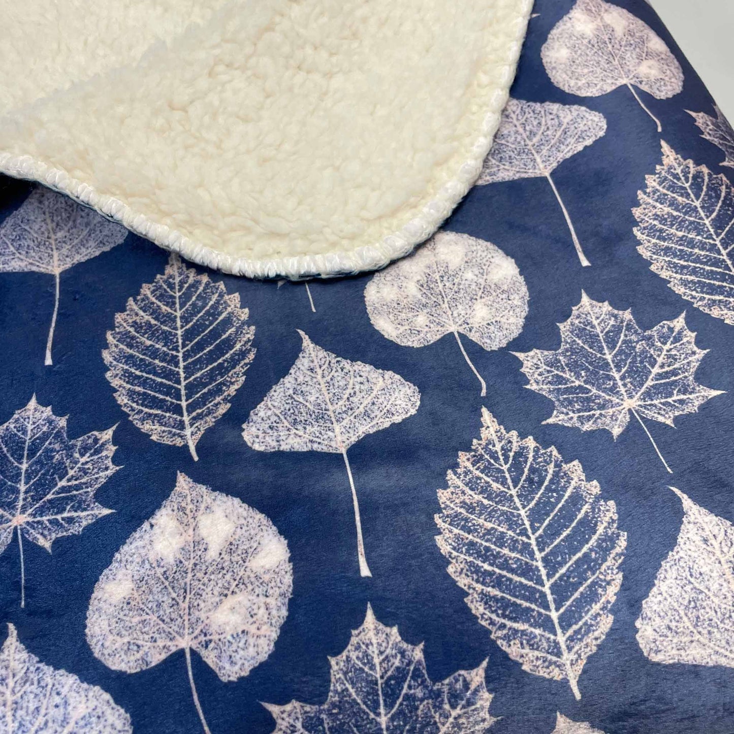 Close-up of a navy blue, leaf-patterned sherpa throw blanket