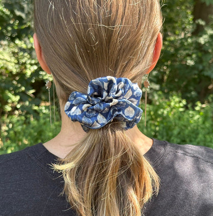 A outdoor photo of a girl wearing a leaf pattern navy satin scrunchie for her ponytail.