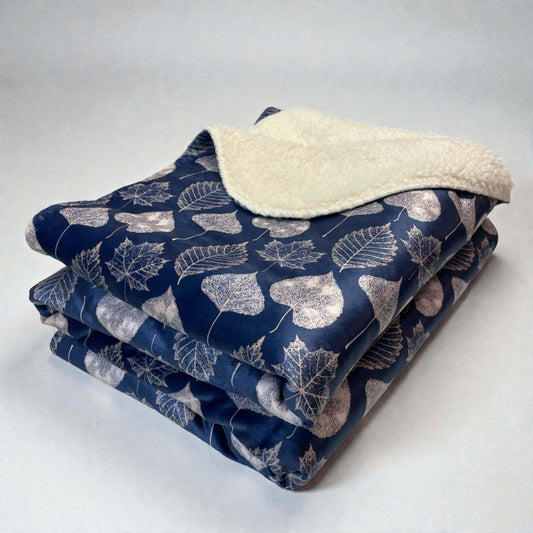A folded navy, leaf-patterned sherpa throw blanket