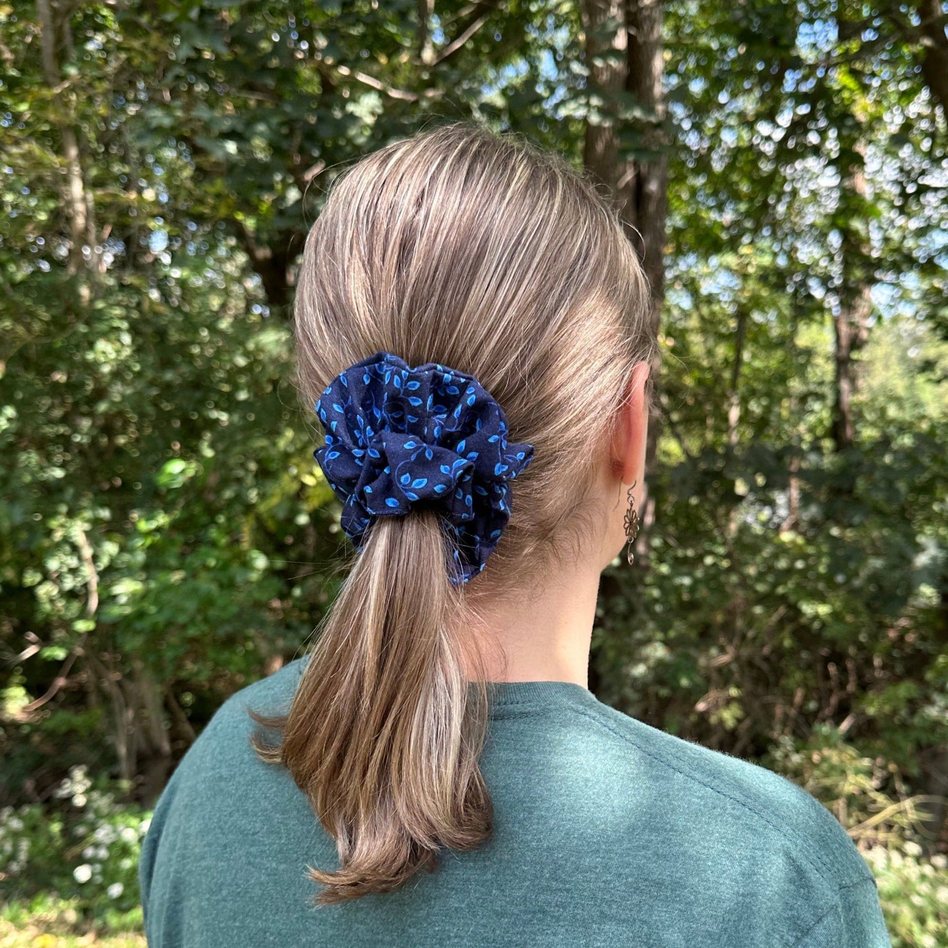 Woman standing outdoors with a pretty navy blue hair scrunchie with a royal blue vine pattern in her ponytail.