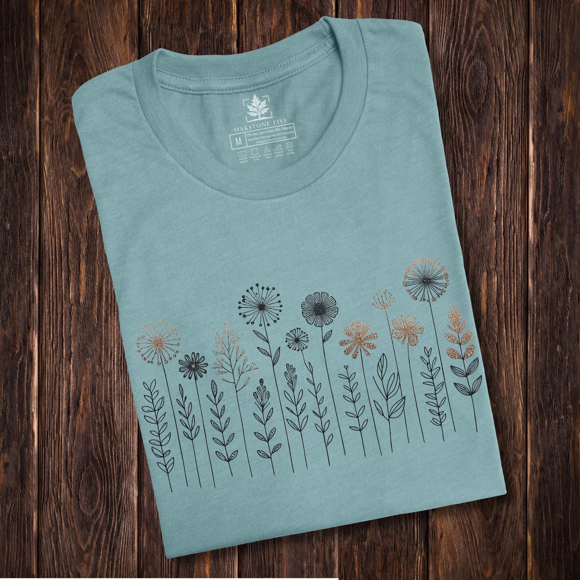 A folded, blueish, cute and charming nordic wildflower shirt for women - great as a gift for gardeners and flower lovers!