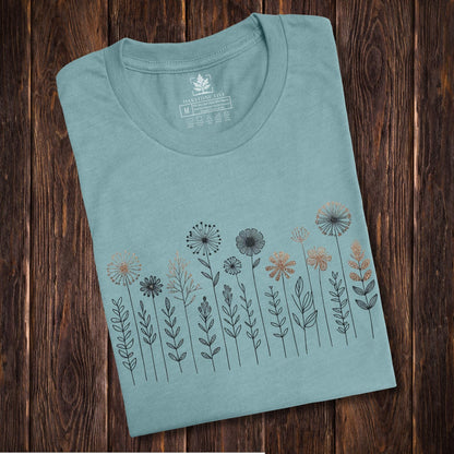 A folded, blueish, cute and charming nordic wildflower shirt for women - great as a gift for gardeners and flower lovers!