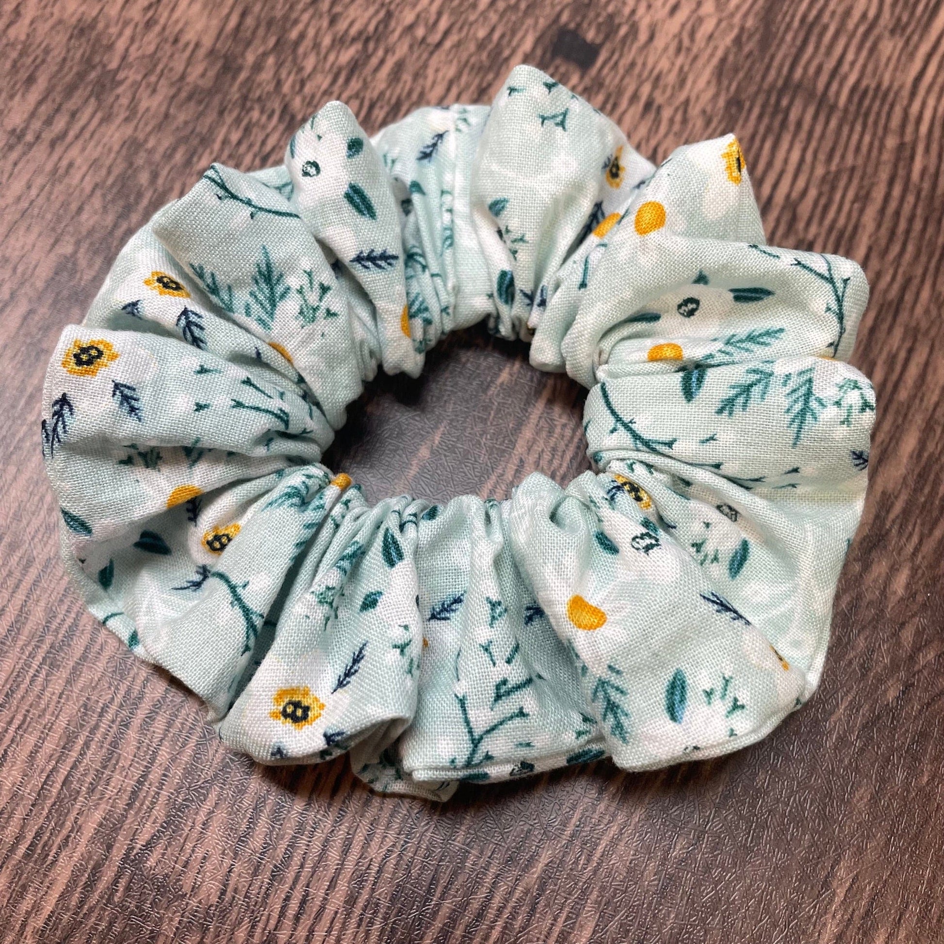 Green floral patterned scrunchie on a wooden background