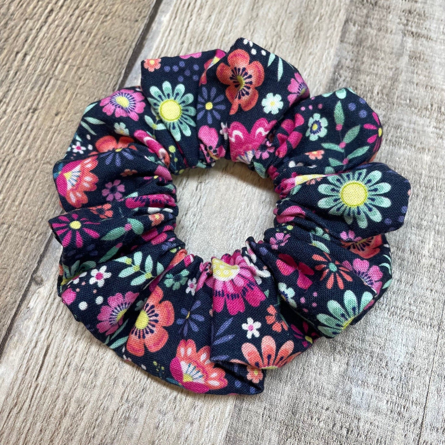 Pink, Green Floral patterned scrunchie on a wood background