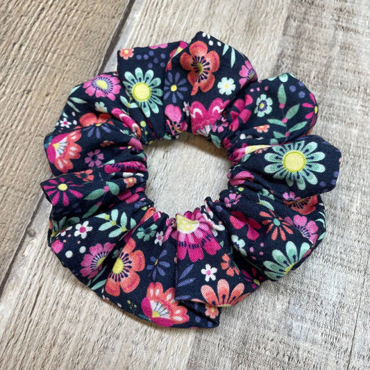 Pink, Green Floral patterned scrunchie on a wood background