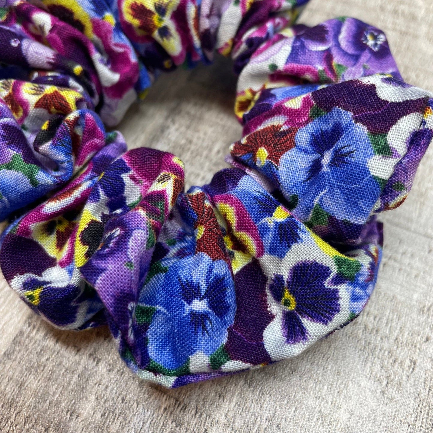 Close-up of a purple, pansies floral patterned hair scrunchie