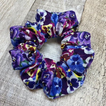 Floral, purple pansies patterned scrunchie on a wood surface