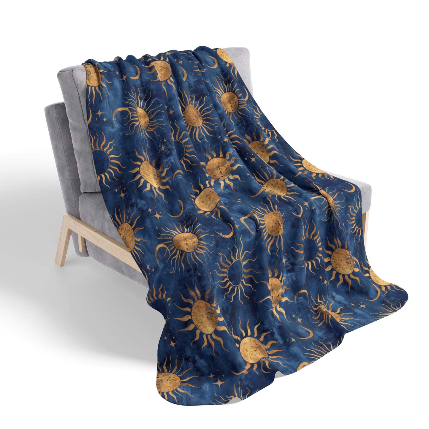 A sherpa blanket featuring a vibrant blue background with a celestial motif of sun, moon, and stars, draped over a chair, on a white background