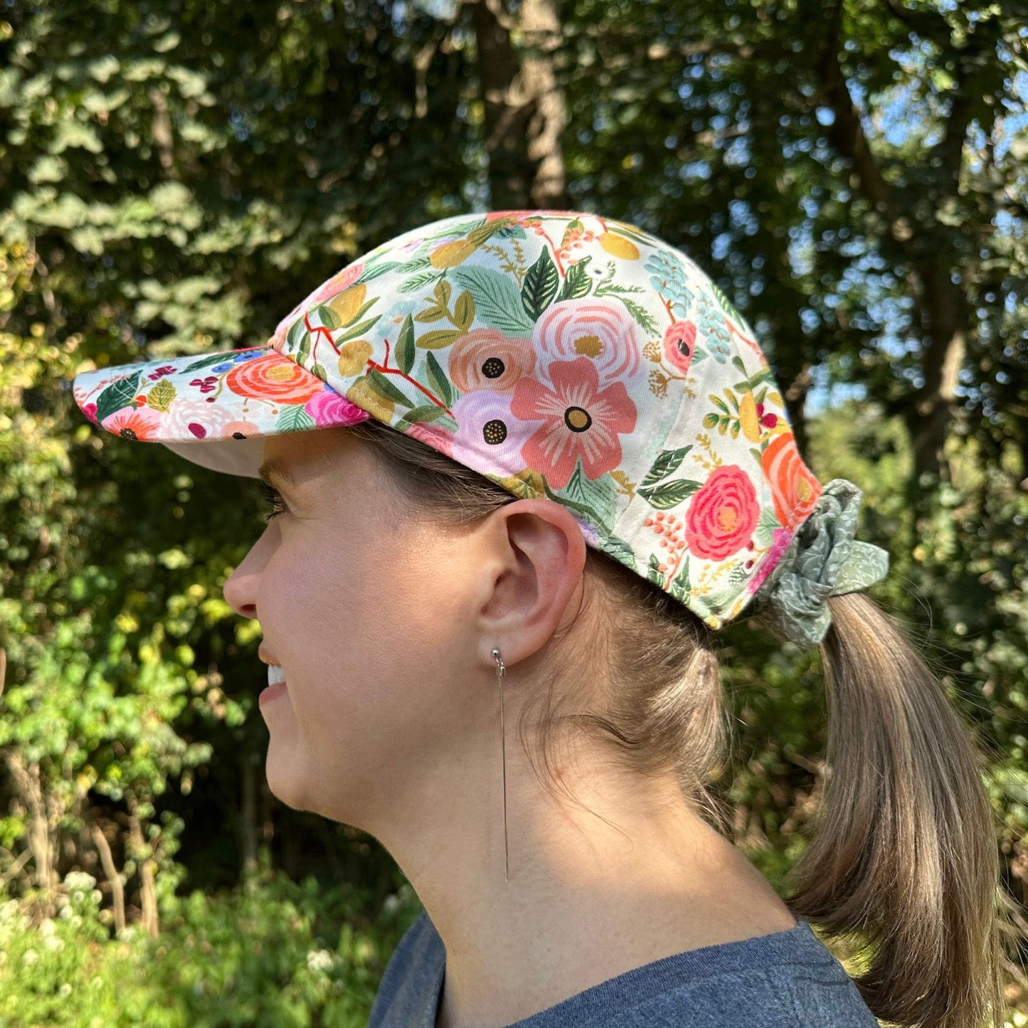 Woman wearing a floral baseball cap with trees in the background