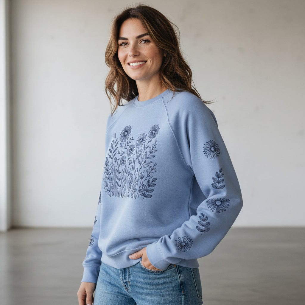 Woman wearing a light purple sweatshirt with floral pattern on front and down the sleeves, against a plain background