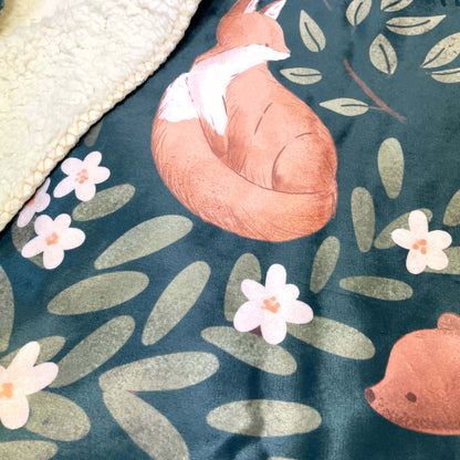 A close-up of a nature-inspired sherpa blanket that features woodland animals