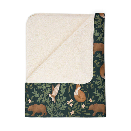 Sherpa blanket with forest-themed pattern featuring bears, foxes, and owls on a white background