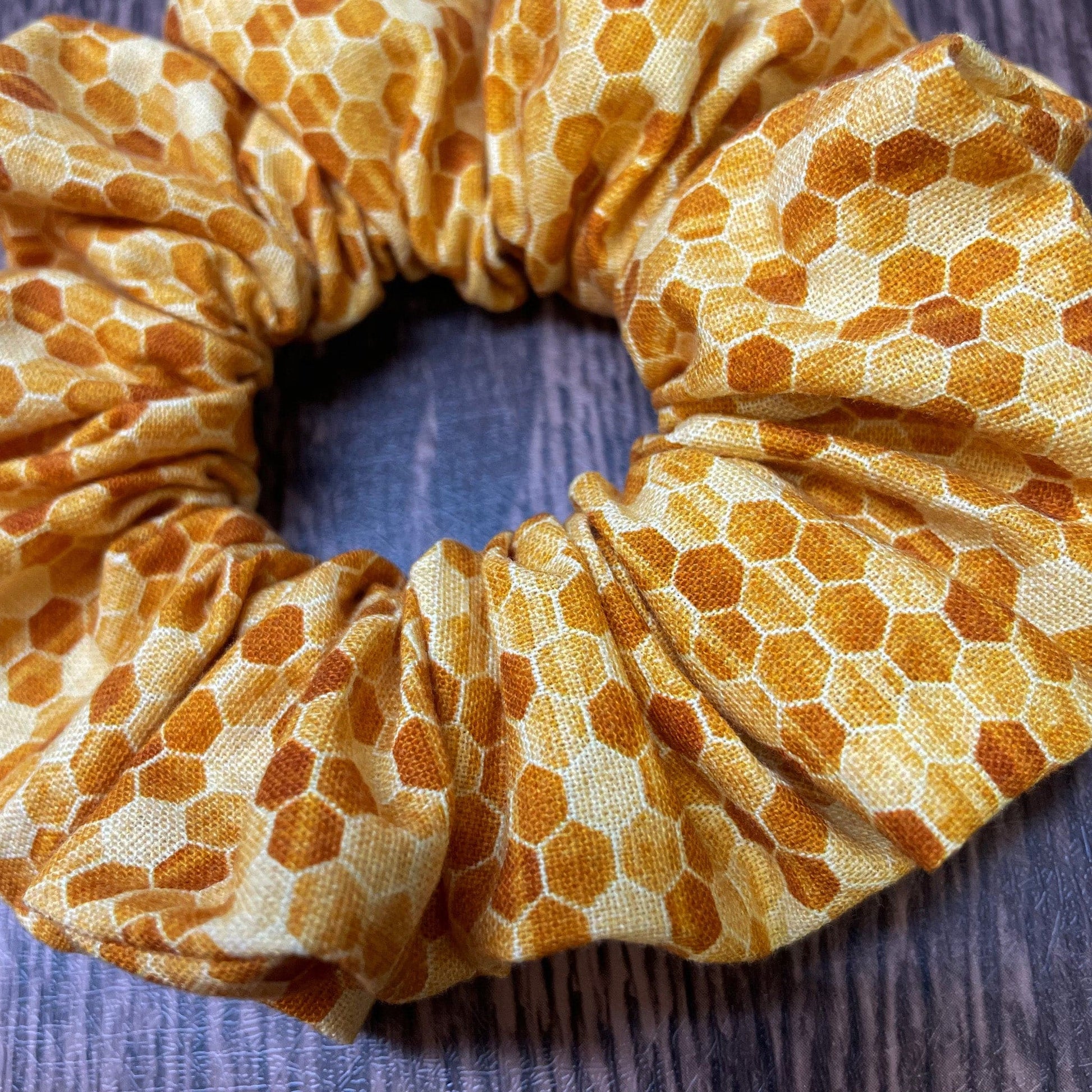Yellow and gold honeycomb patterned scrunchie on a wood background