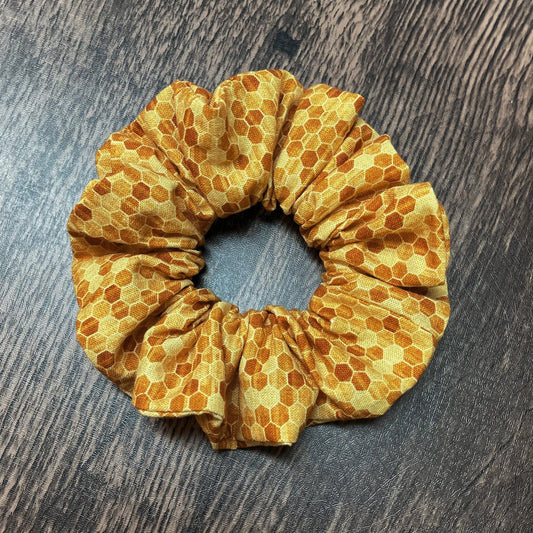 Yellow scrunchie with honeycomb pattern on a wooden surface