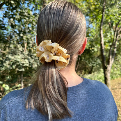 Woman wearing a cute, yellow honeybee scrunchie that has flowers and bees on a honeycomb pattern